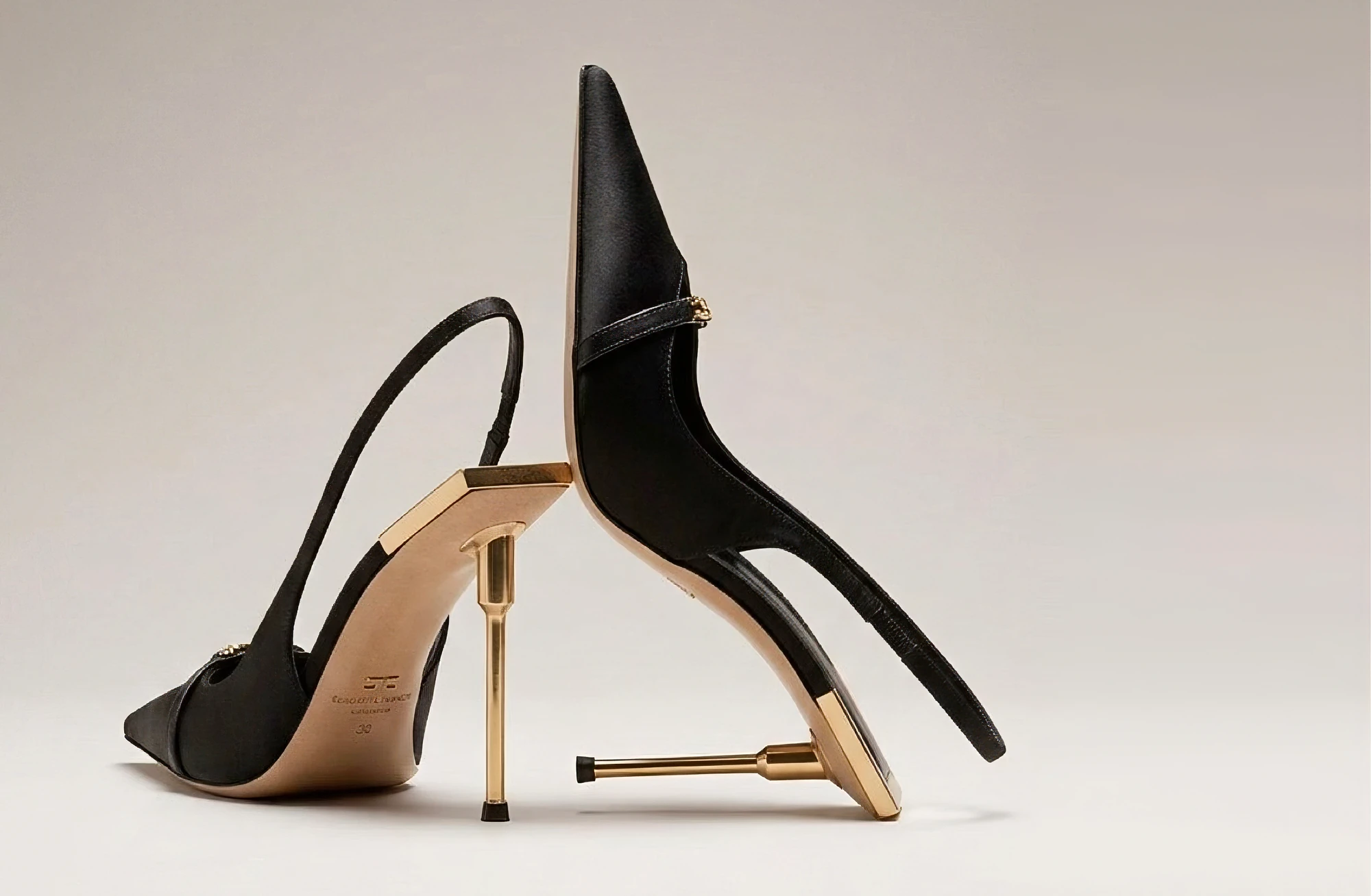 Scarpe nere con tacchi dorati in una composizione scultorea.
